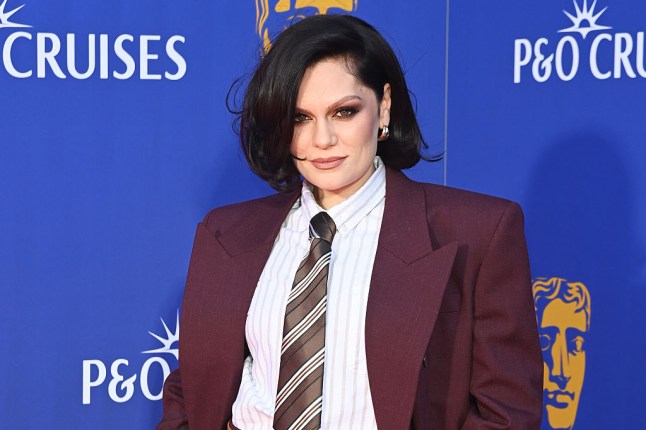 Jessie J at the BAFTAs wearing a white shirt and a burgundy tie and jacket