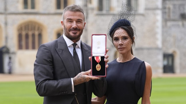 David and Victoria Beckham at Windsor Castle, holding up the medal he received for his knighthood.