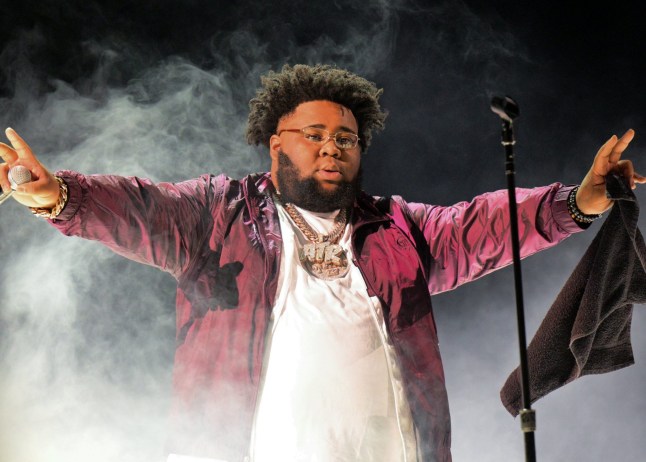 Rapper Rod Wave performs onstage with hands in air.